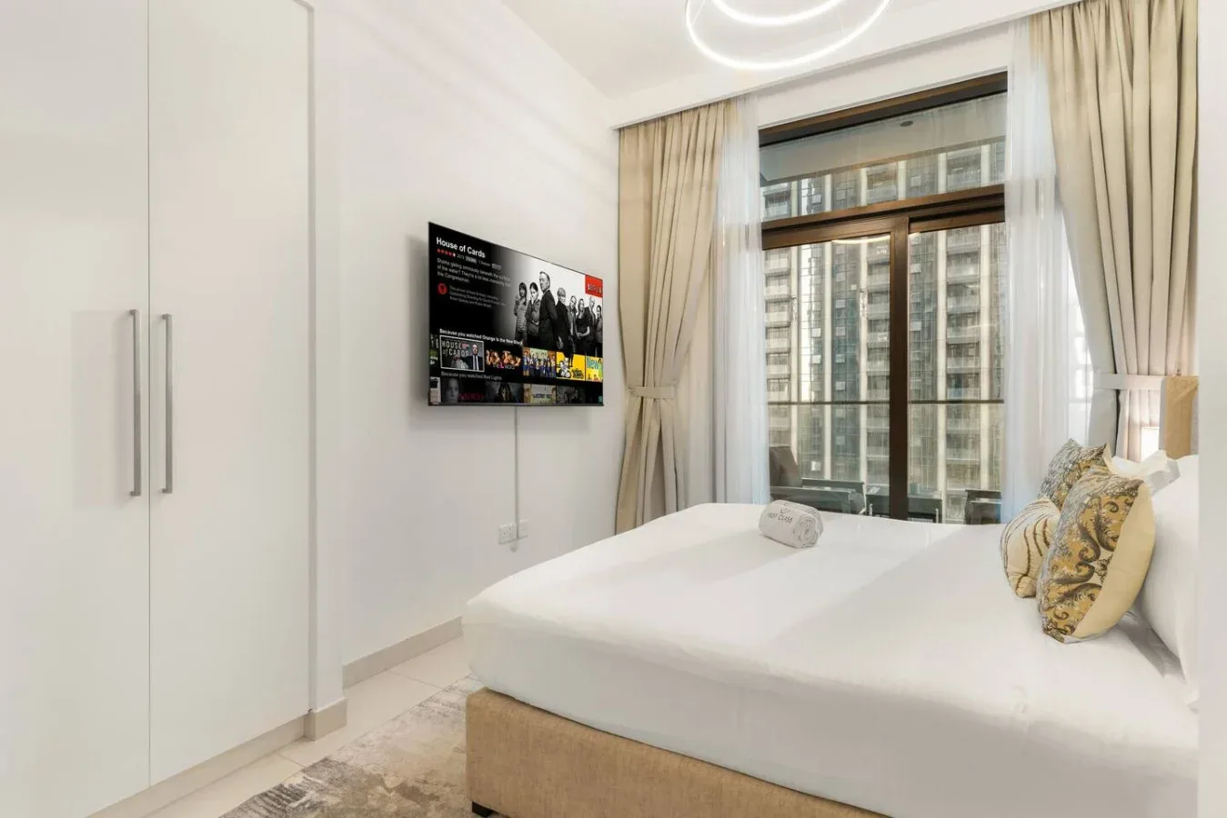 Un dormitorio luminoso con una cama junto a una gran ventana con cortinas.