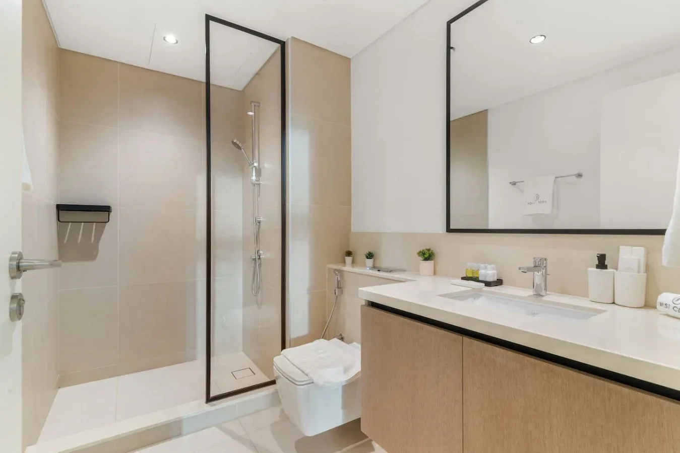 Baño moderno con ducha de vidrio y un largo mueble de lavabo.
