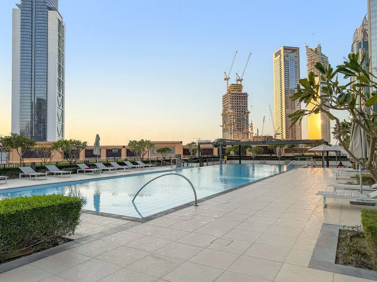Una piscina en la azotea y una terraza pavimentada dan a edificios de la ciudad.