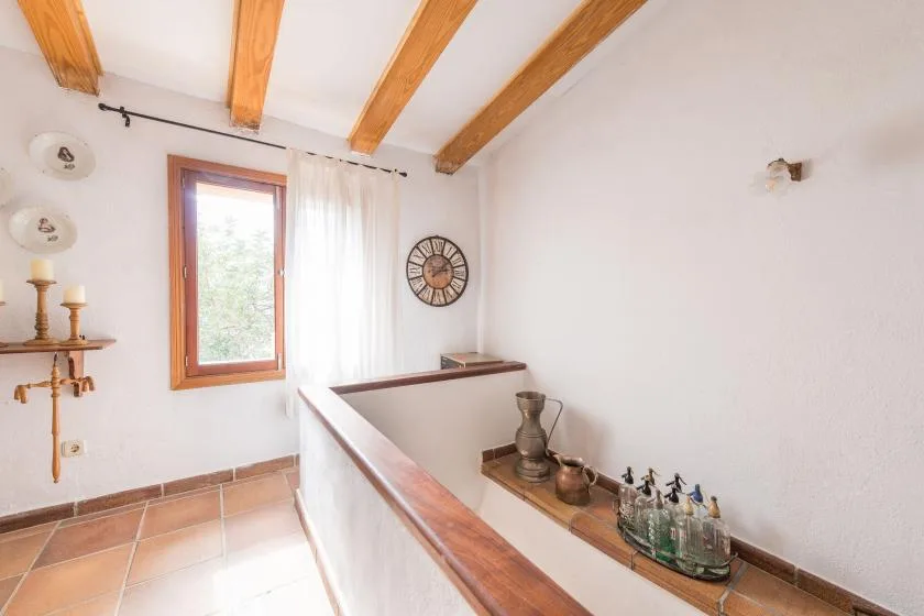 An indoor landing with a window, exposed wooden ceiling beams, and a display ledge.