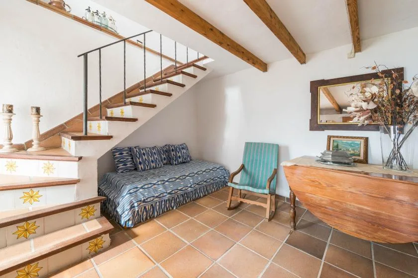 A living area with a patterned daybed and a staircase.