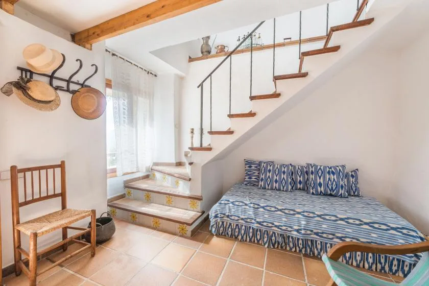 A bright sitting area with patterned seating beside a staircase and a sunlit window.