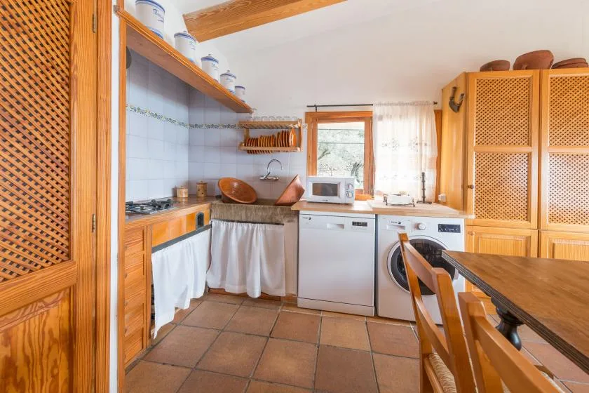 A kitchen with wooden cabinets, a tiled floor, and a dining table.