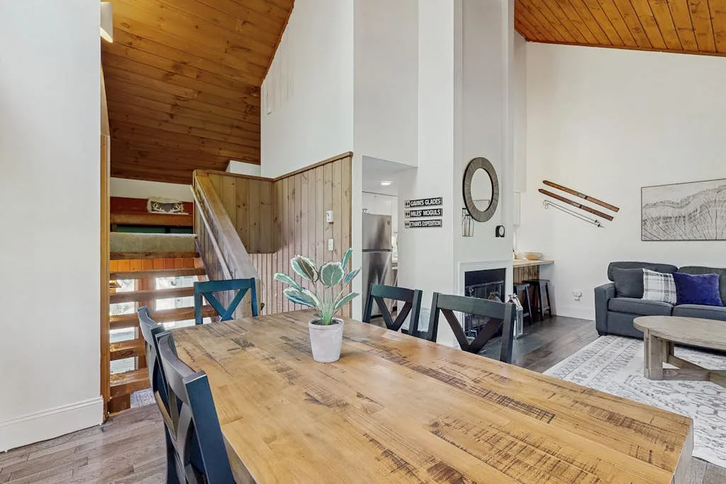 Comedor con una mesa de madera y asientos junto a una sala de estar.