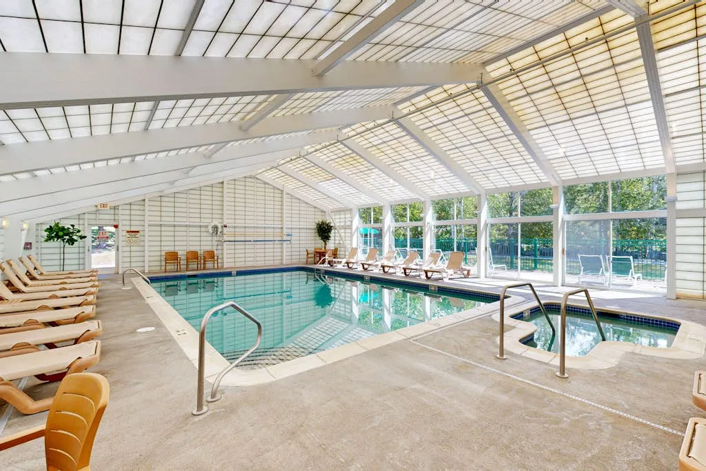 Una piscina cubierta con asientos reclinables bajo un techo de vidrio.