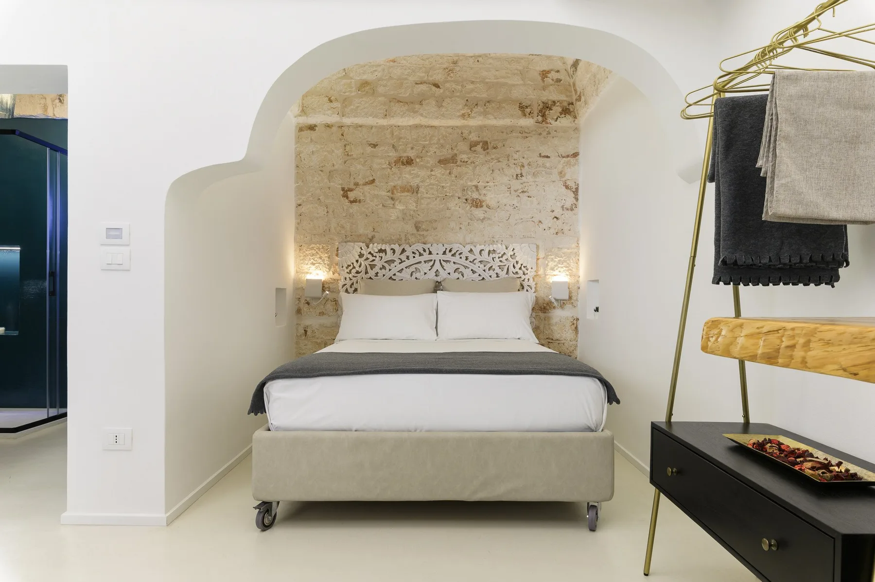 Un dormitorio con una cama bajo un arco curvo y toallas colgadas cerca.