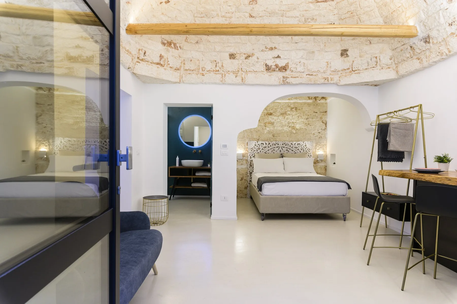 Un dormitorio con una cama, un techo curvo de textura pétrea y un escritorio.
