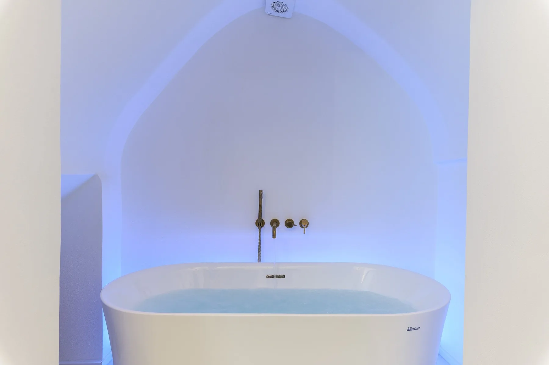 Una bañera está bajo un nicho arqueado con iluminación azul.