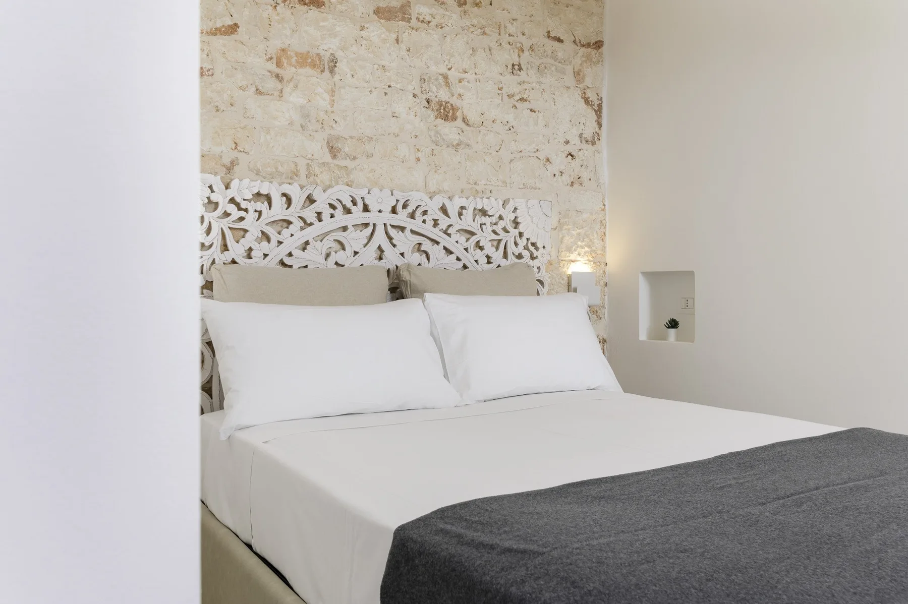 Un dormitorio con ropa de cama blanca y un cabecero tallado ornamentado.