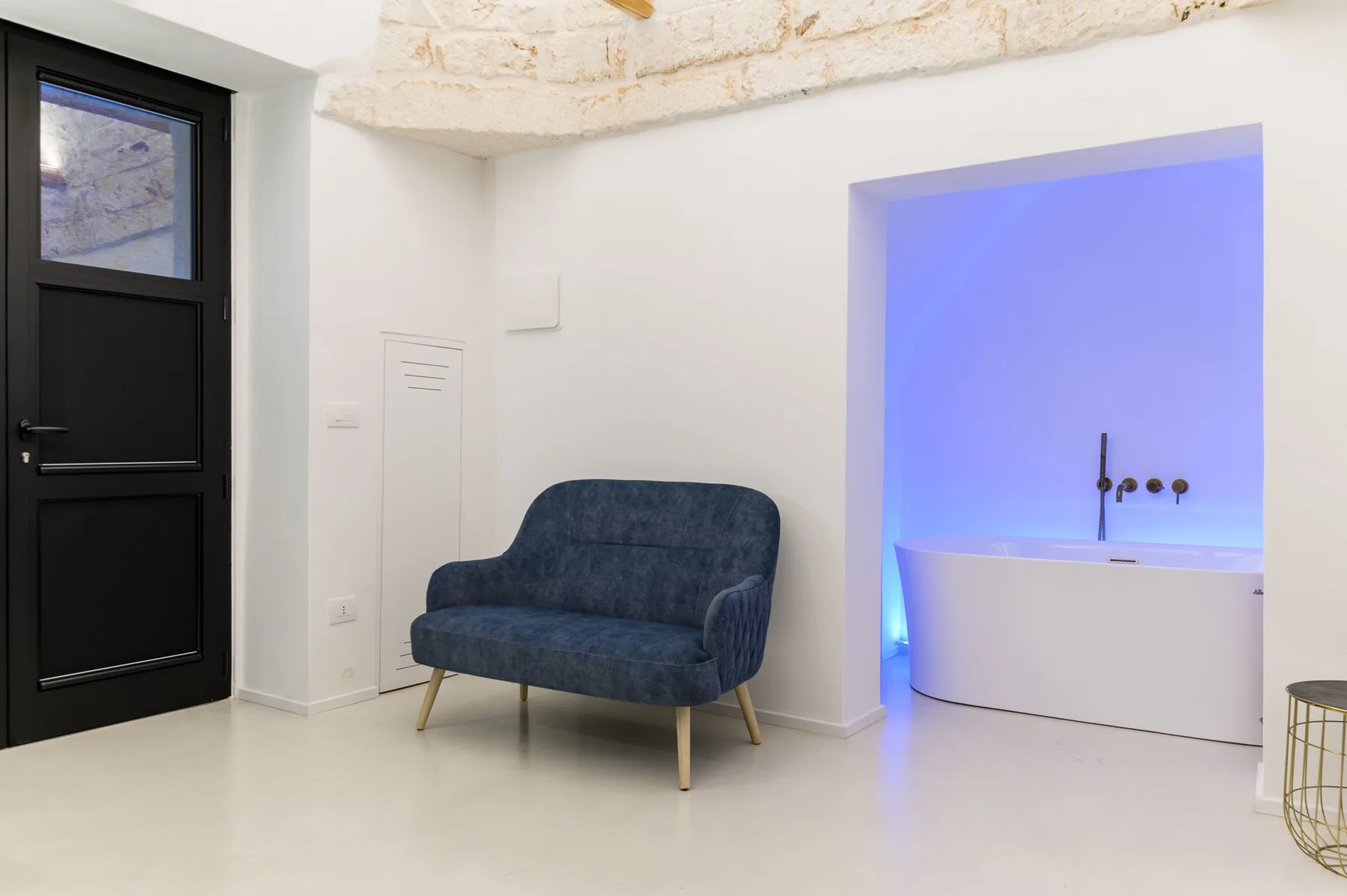 Una zona con asientos azules junto a una bañera en una habitación luminosa.