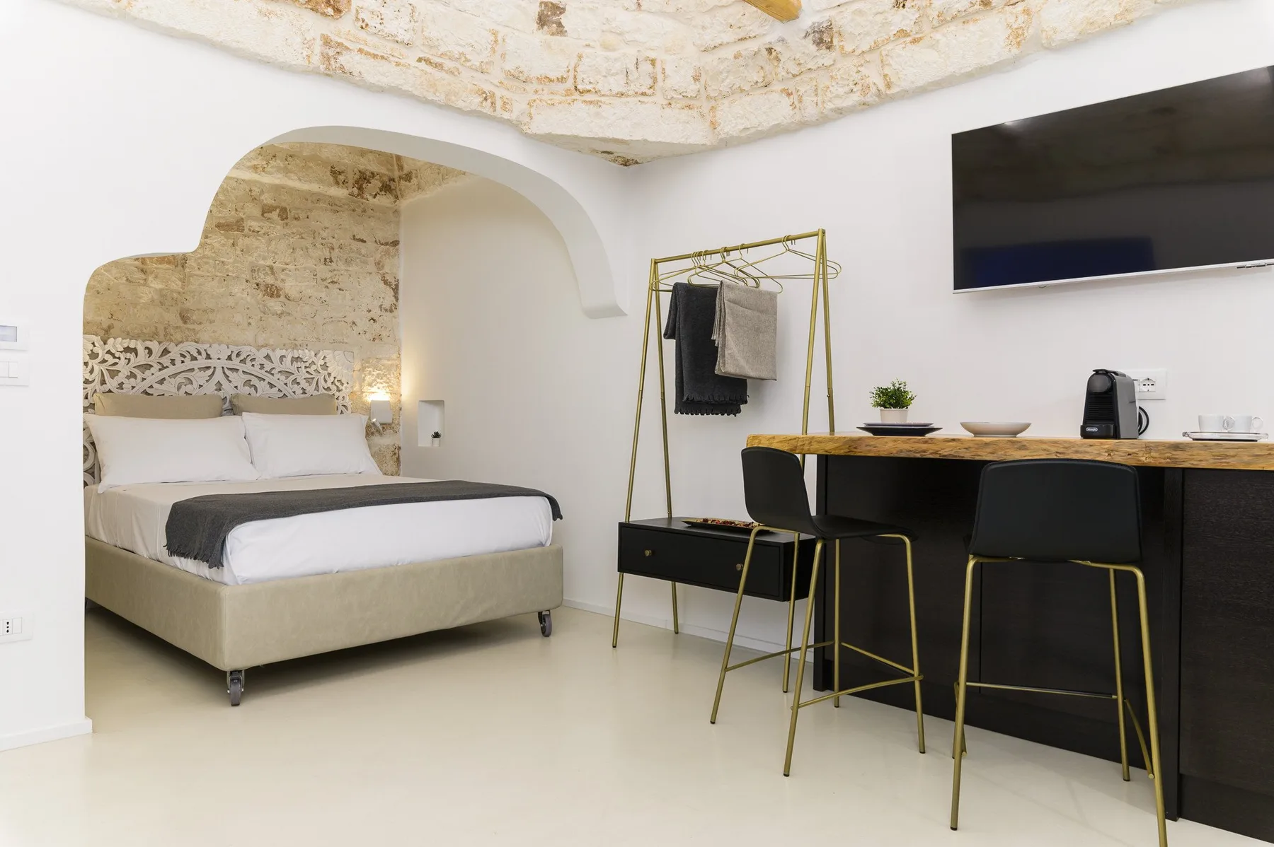 Un dormitorio con una cama, una barra para comer y un televisor en la pared.
