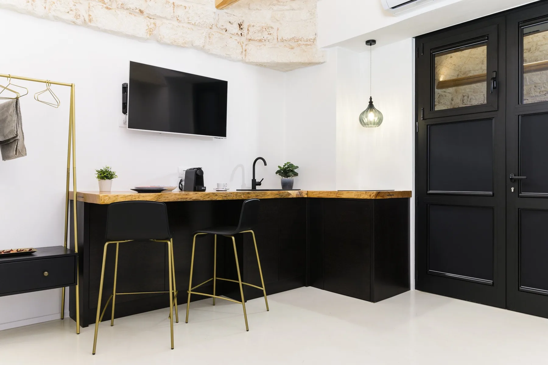 A modern kitchenette with a counter, seating, and dark doors.