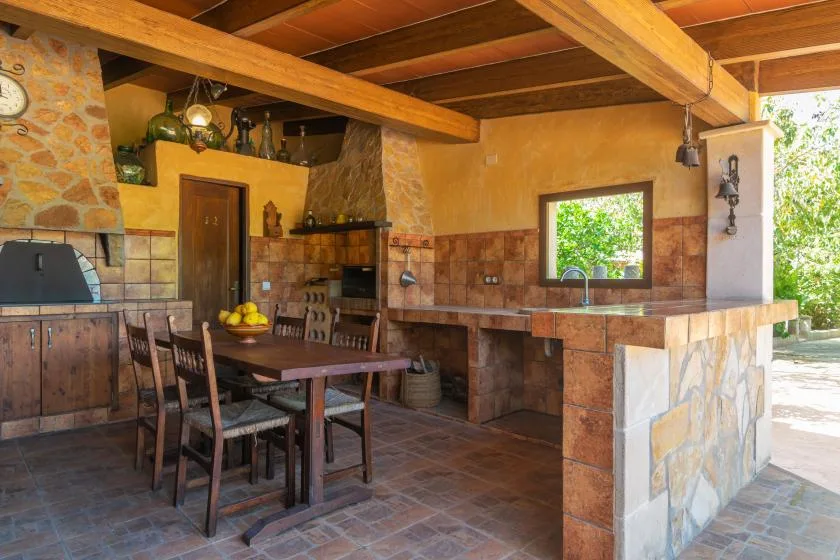 A rustic dining area with a wooden table beside a stone counter.