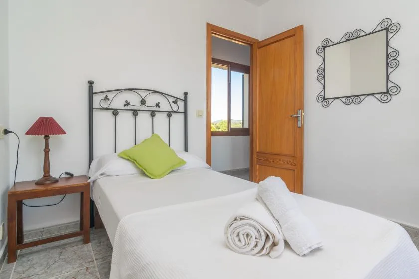 A bedroom with a bed, green accent pillow, and open wooden door.