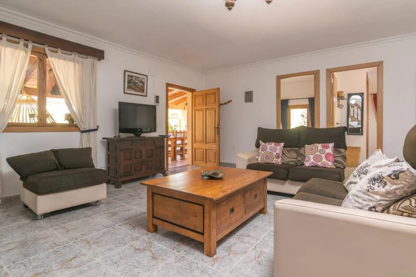 A living room with seating around a wooden coffee table and a television.