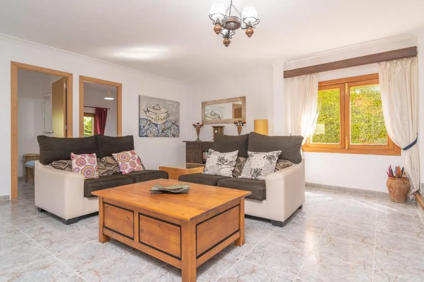 A bright living room with seating, a wooden coffee table, and a large window.