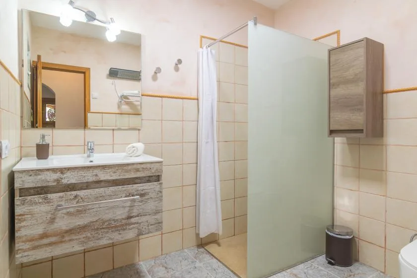 A tiled bathroom with a sink vanity, mirror, and shower.