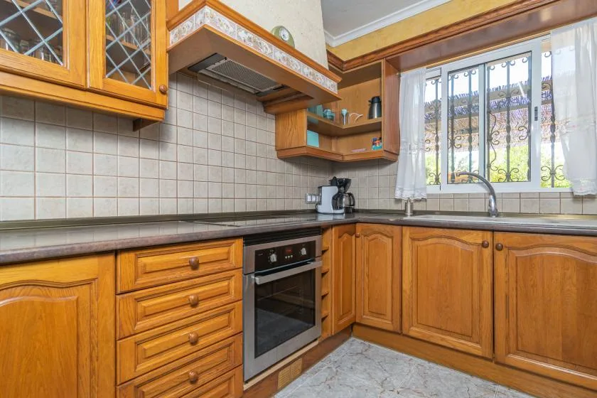 A kitchen with wooden cabinets, a tiled backsplash, and a window.