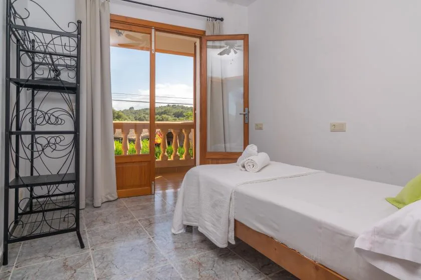A bedroom with a neatly made bed beside an open balcony door.