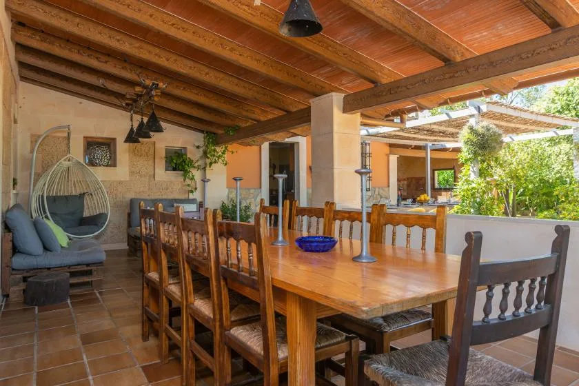 Comedor cubierto con una mesa larga de madera bajo vigas vistas.
