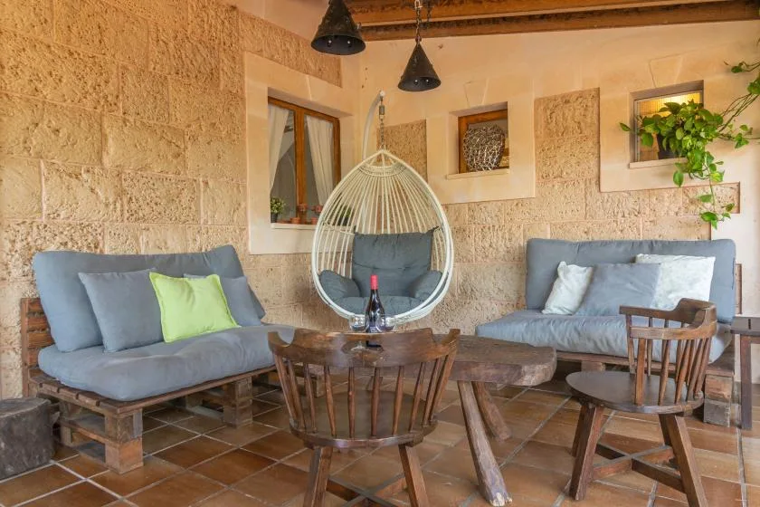 A rustic indoor seating area with gray cushions, wooden furniture, and a hanging chair.