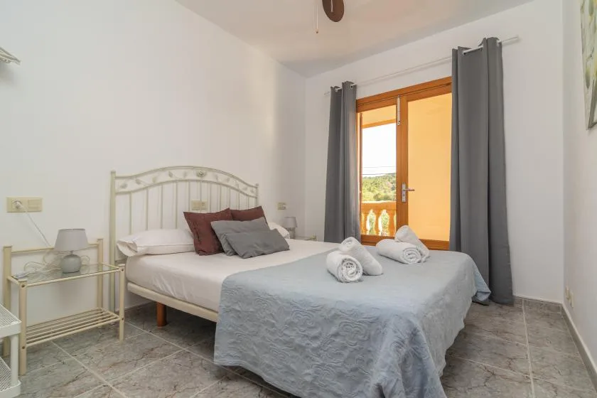 A bedroom with a neatly made bed beside a bright glass door.