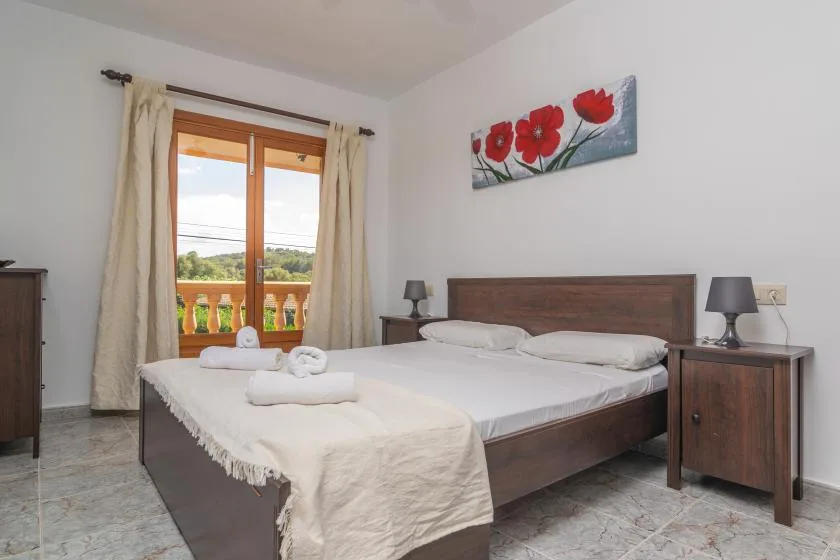 A bedroom with a double bed, bedside tables, and a window with curtains.
