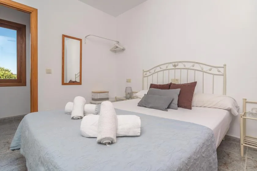 A bedroom with a neatly made bed and folded towels.