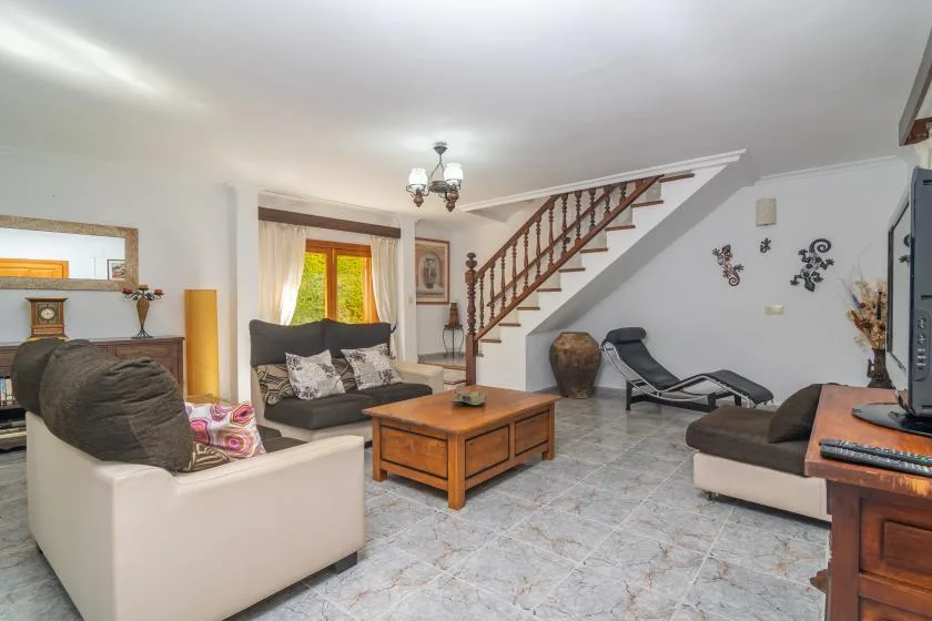 A living room with sofas, a coffee table, and a staircase.