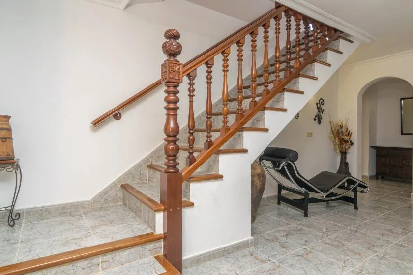 An interior staircase with a wooden railing beside a reclining chair.