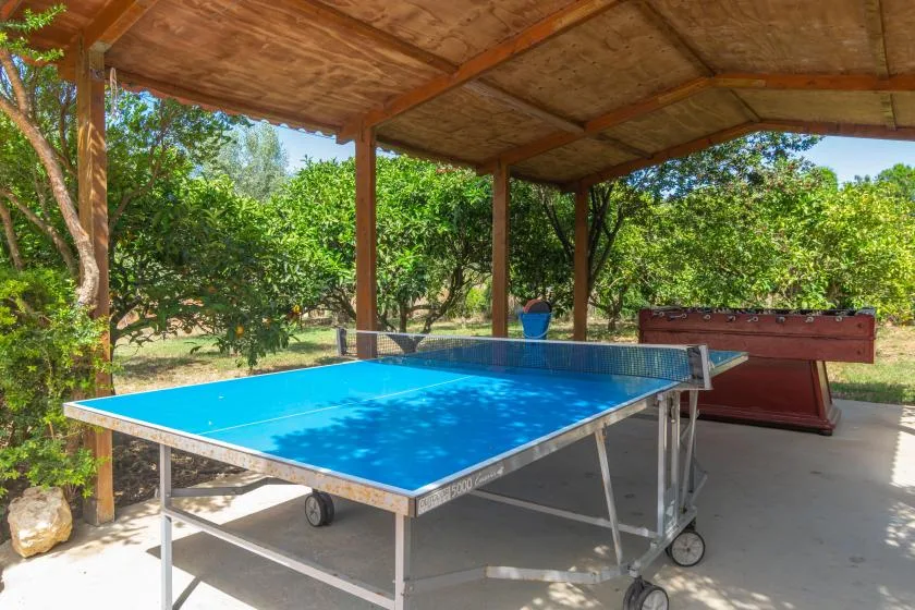 A covered outdoor recreation area with a table tennis table and foosball table.
