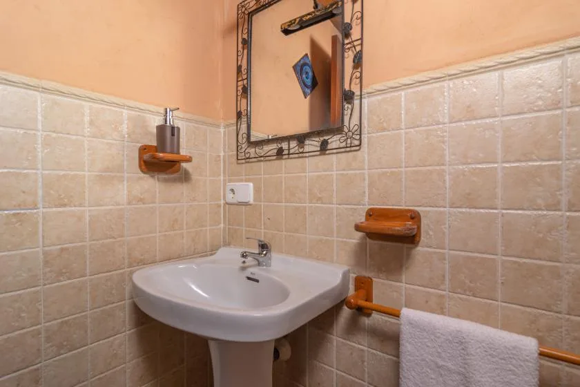 A tiled bathroom sink sits beneath a framed mirror.