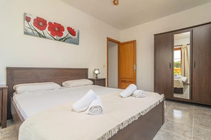 A bedroom with a double bed and a wardrobe with mirrored doors.