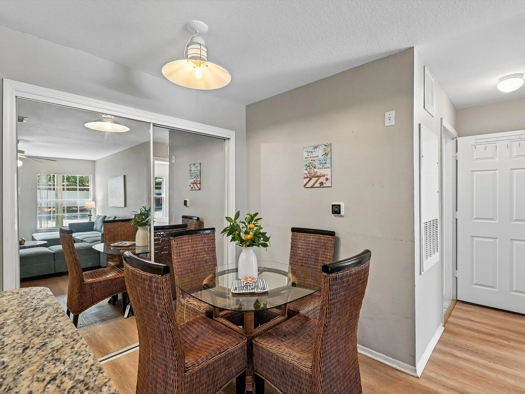 A dining area with wicker seating around a glass-topped table.