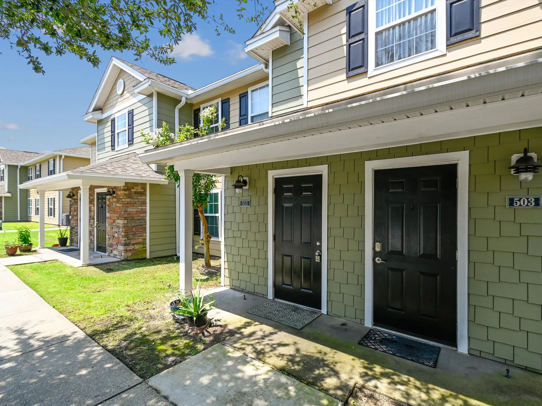 The exterior of a two-story residential building with dark entry doors and a covered walkway.
