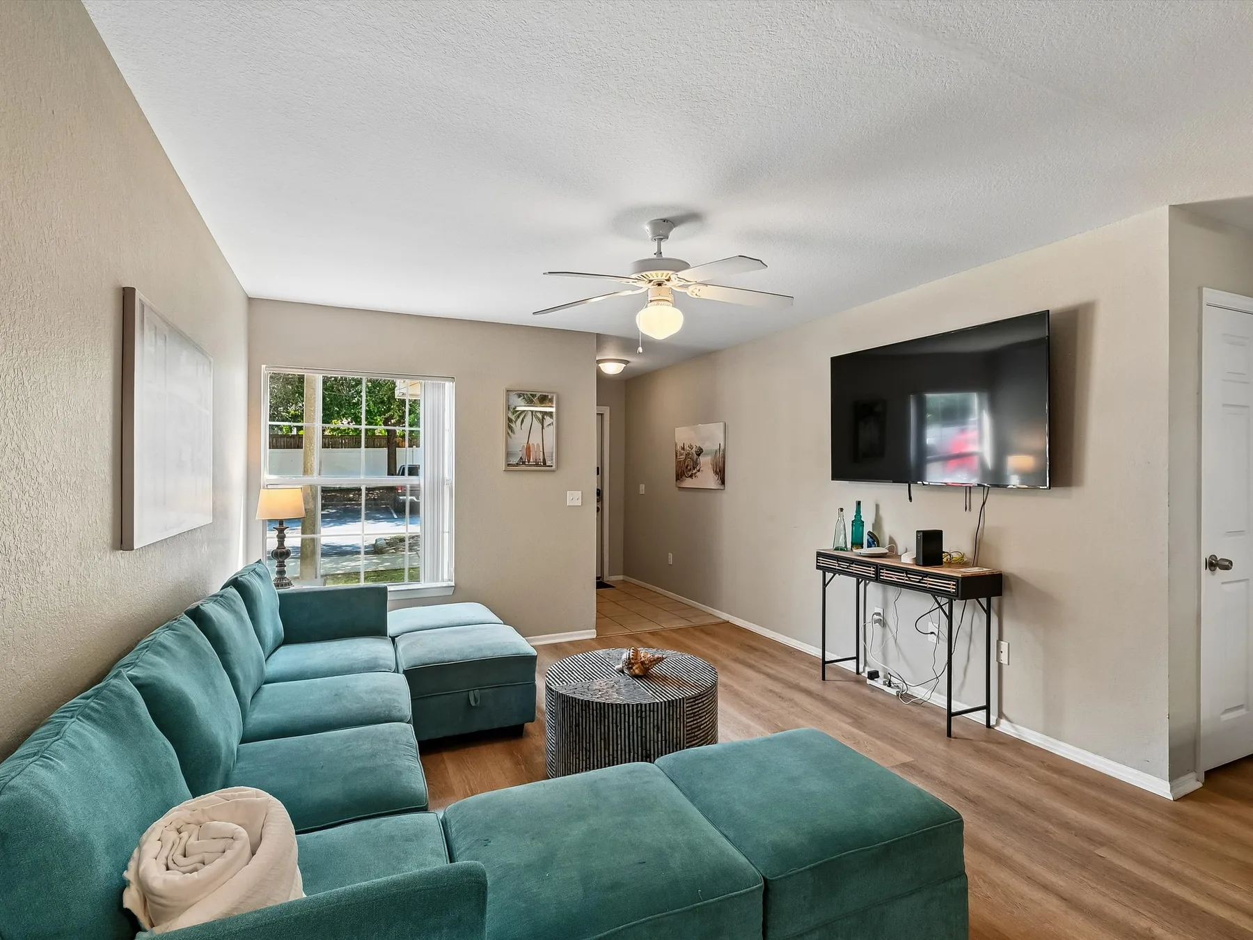 Living room with teal seating, a television, and a window.