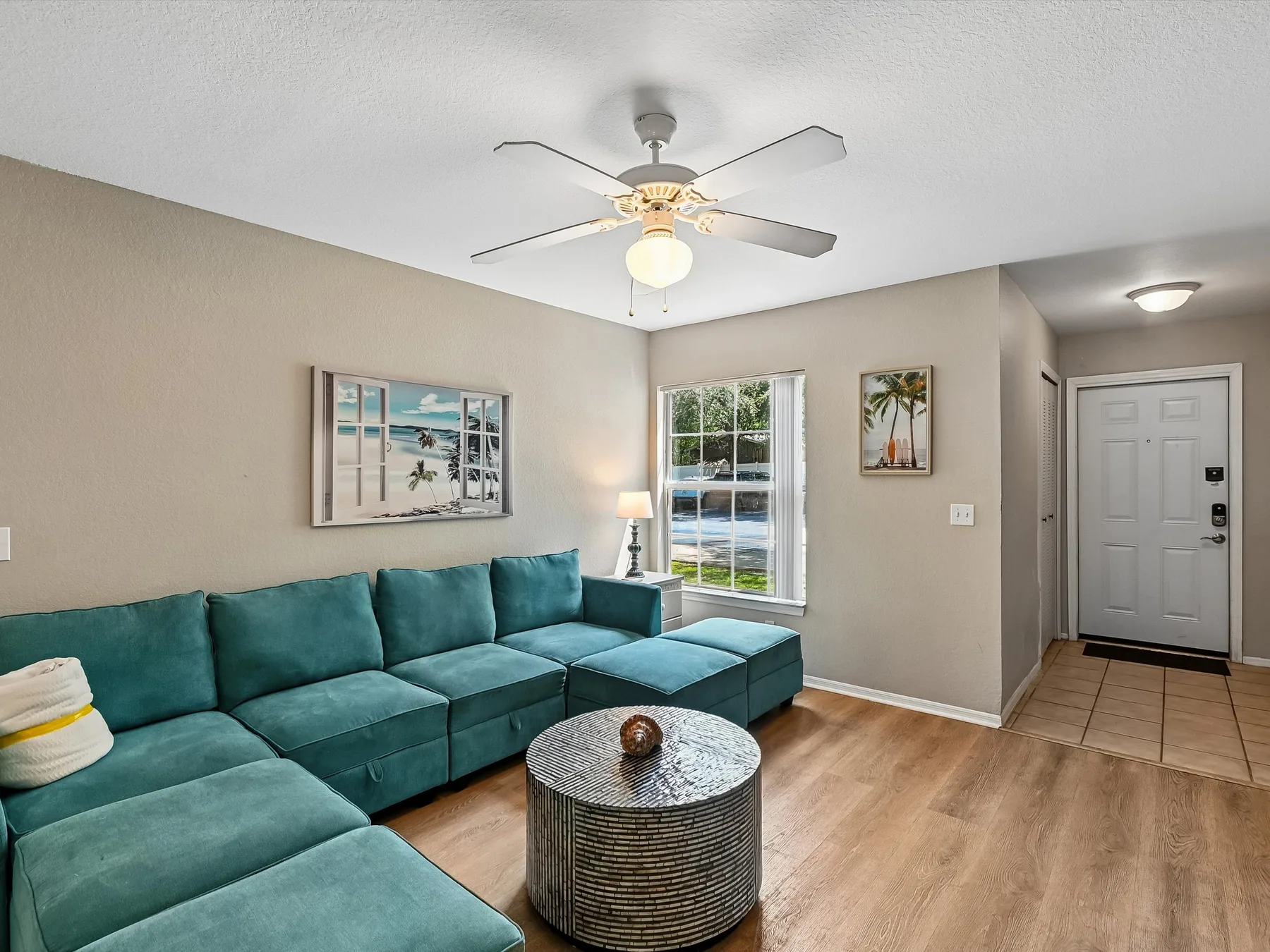 A living room with teal seating, a coffee table, and a ceiling fan.