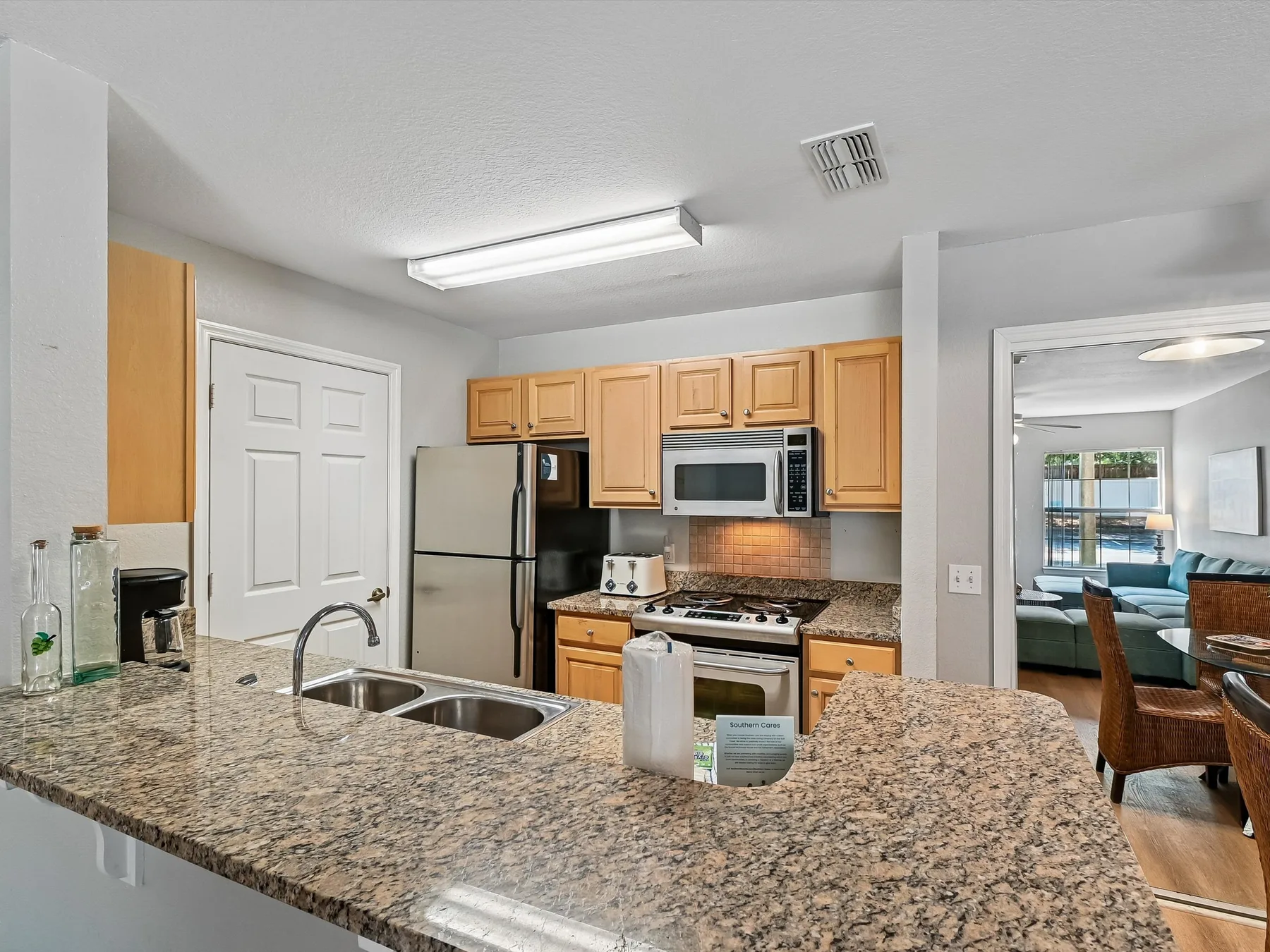 A kitchen with wooden cabinets, stainless steel appliances, and a granite island.