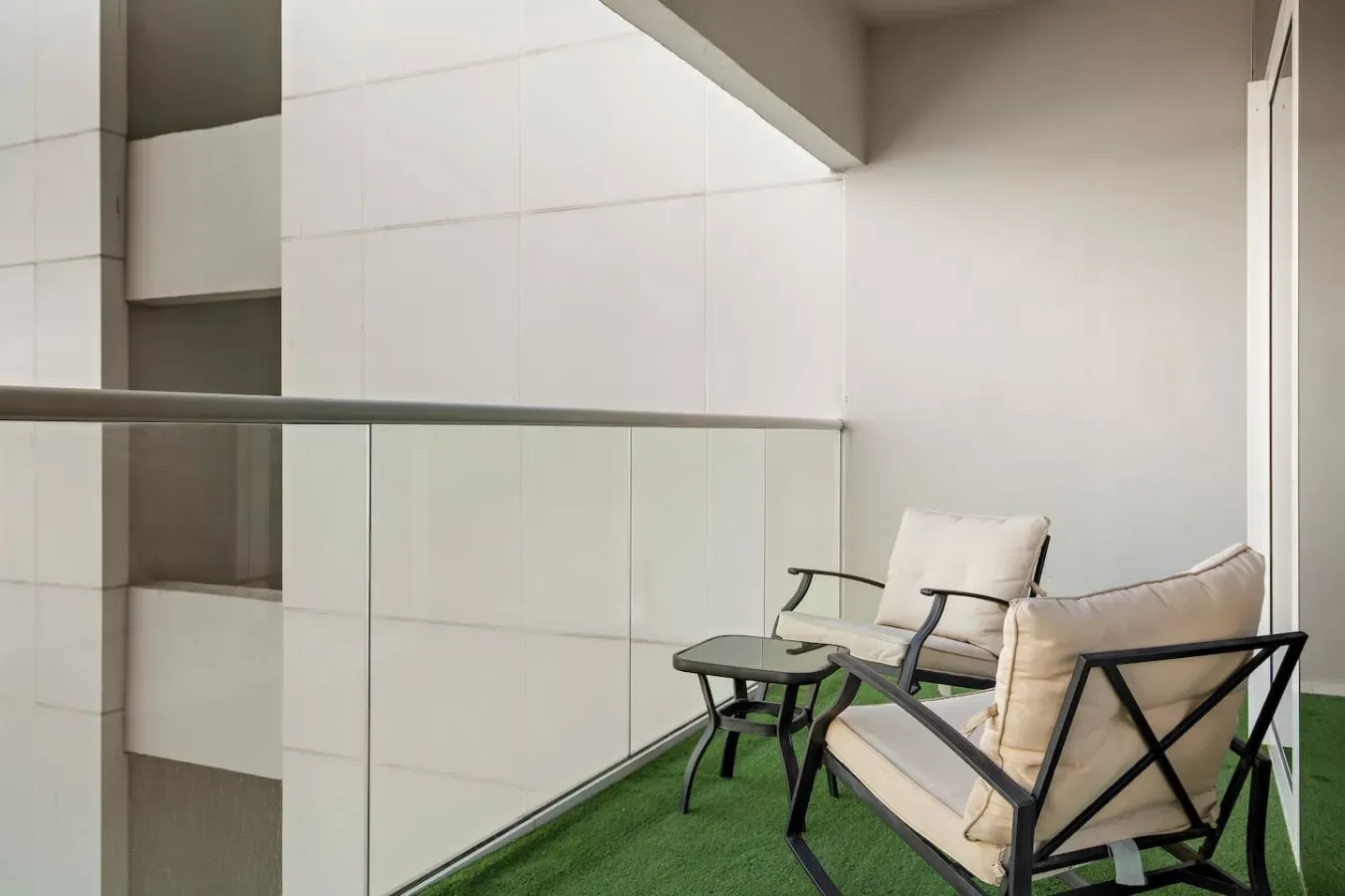 Una zona de asientos con sillones acolchados y una mesa pequeña sobre suelo verde.