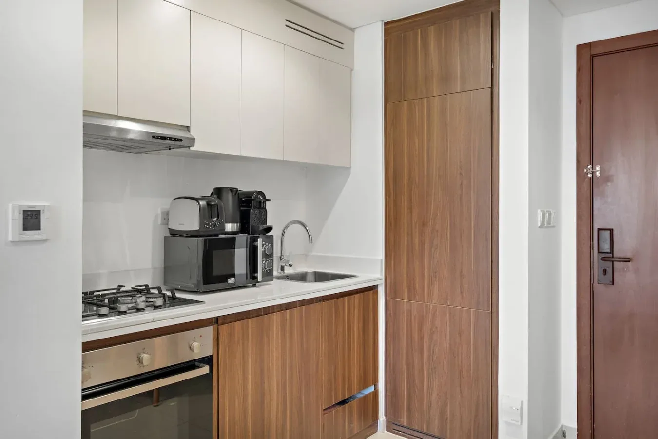 Una cocina compacta con gabinetes de madera, una estufa y electrodomésticos sobre la encimera.