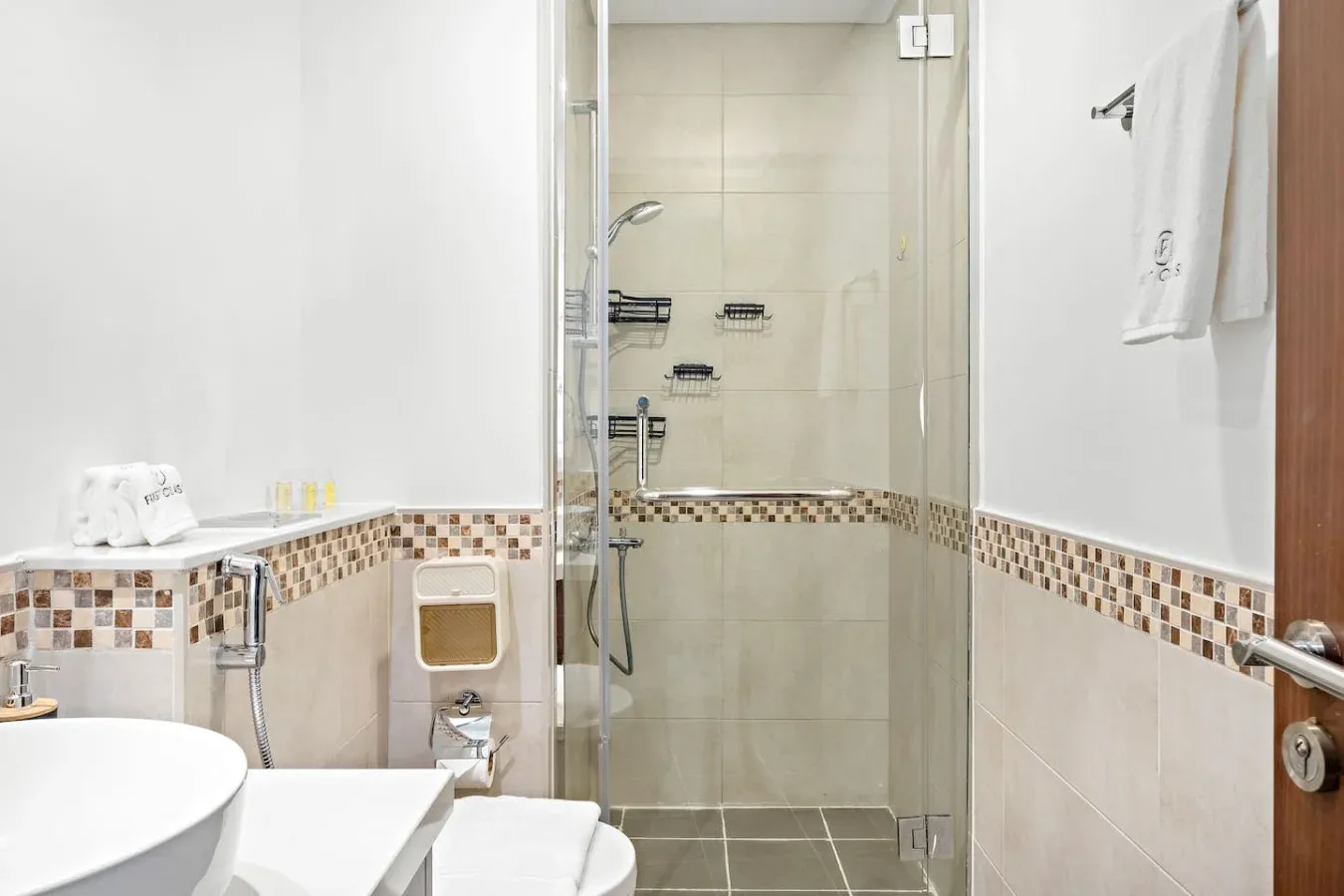 Un baño con azulejos, una ducha de vidrio y un lavabo blanco.