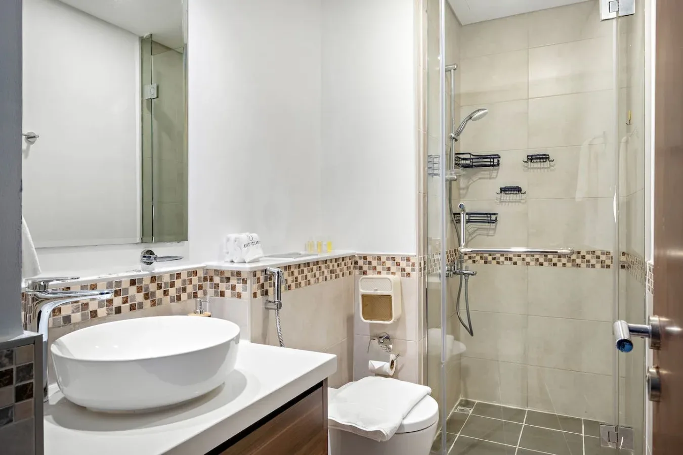 Un baño con lavabo, inodoro y ducha con mampara de vidrio.