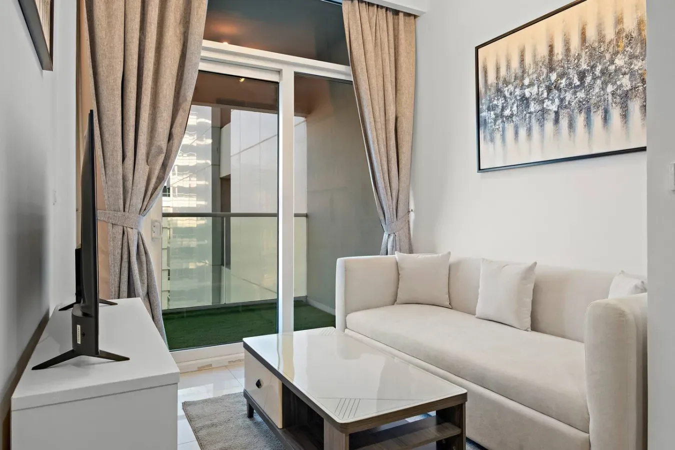 Una sala luminosa con sofá blanco, mesa de centro y puertas de vidrio.