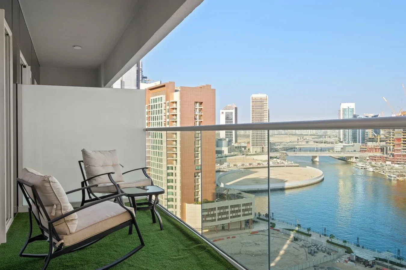 Asientos en un balcón con vistas a edificios y aguas azules.