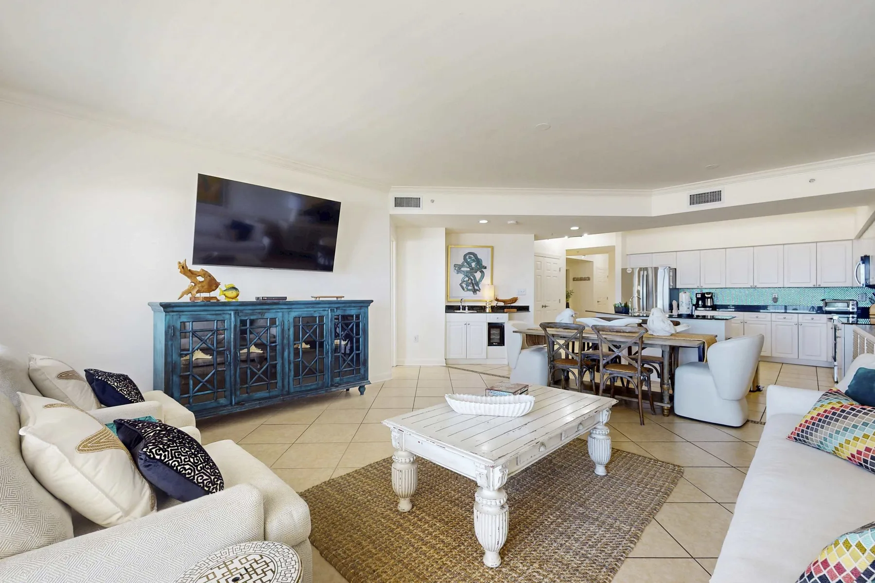 A bright open-plan living and dining area with a white coffee table and kitchen beyond.
