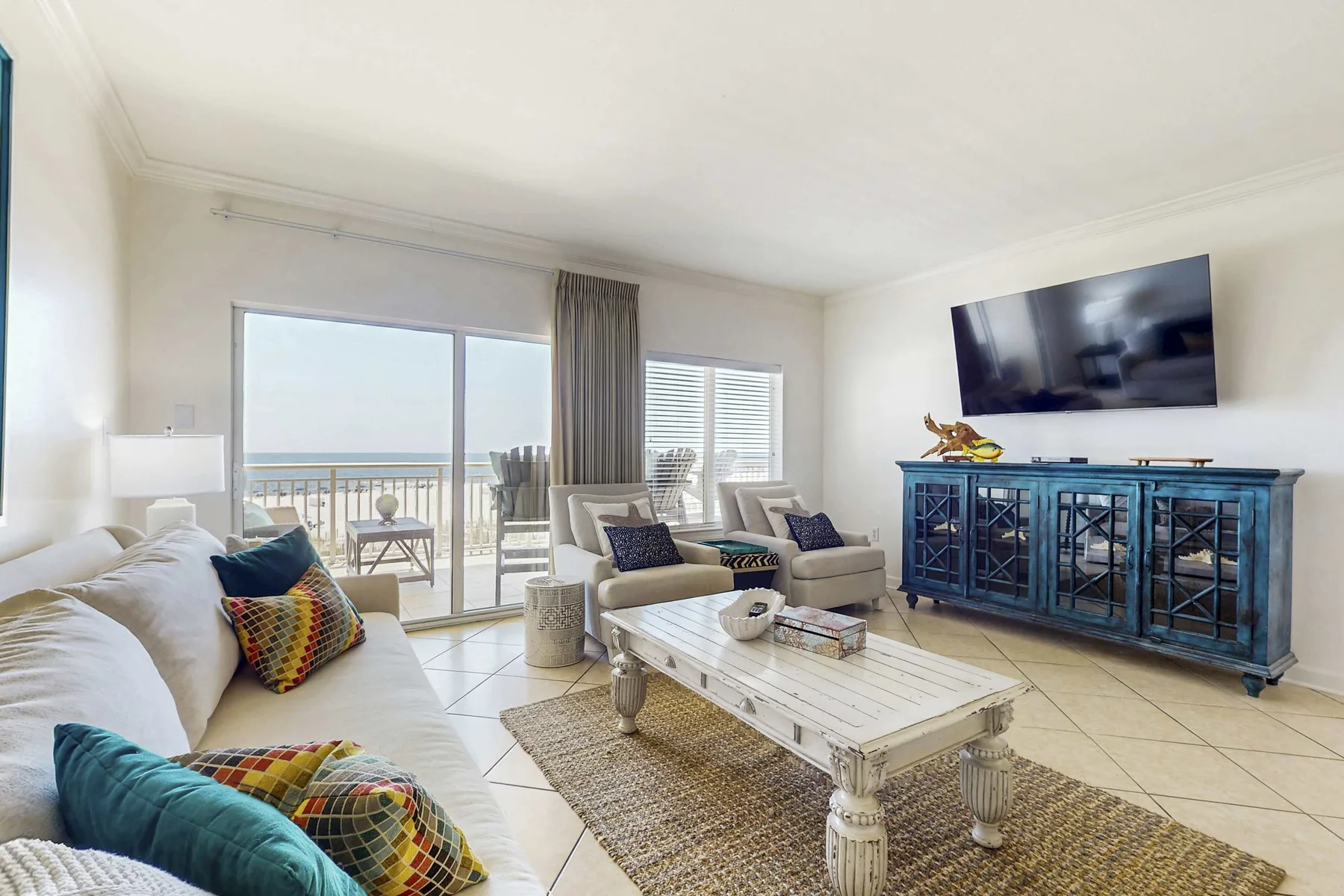 A bright living room with seating, a coffee table, and a balcony view.
