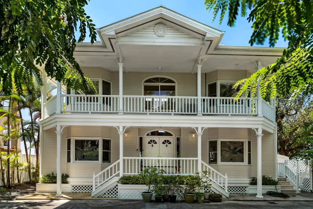 Una casa de dos plantas con una amplia galería blanca y escalones delanteros.