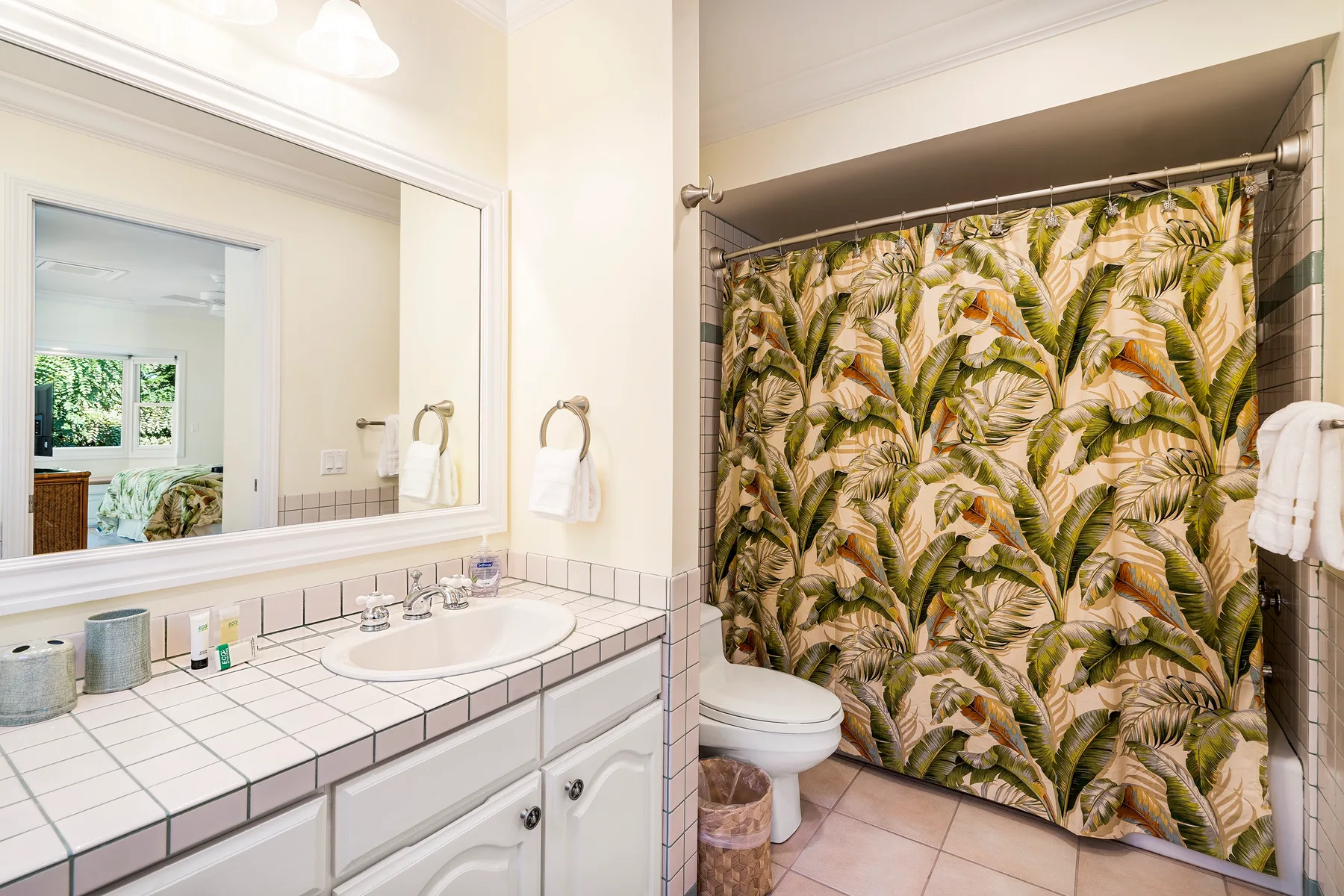Un baño con un lavabo alicatado y una cortina de ducha estampada.