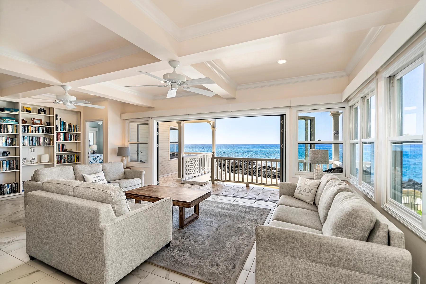 Una sala luminosa con asientos y amplias ventanas con vista al mar.