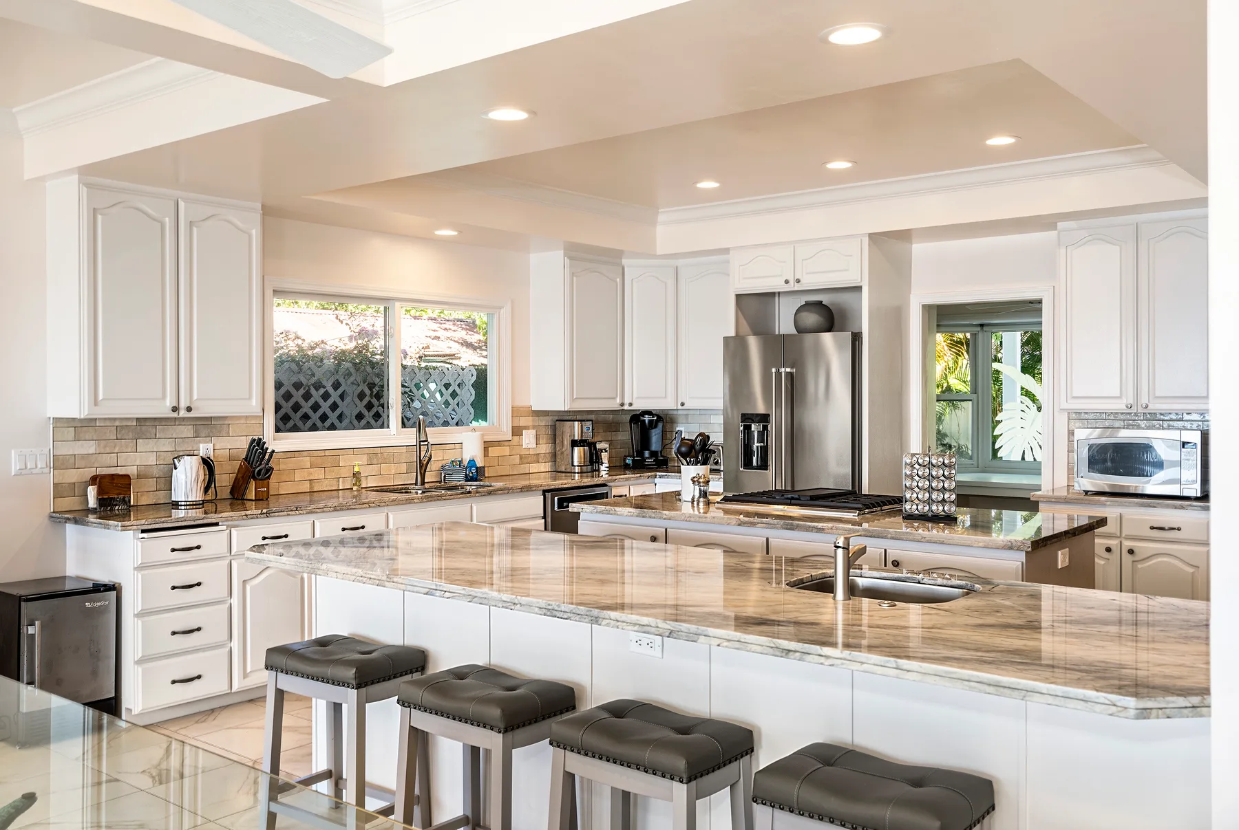 Una cocina luminosa con gabinetes claros, una isla grande y electrodomésticos de acero inoxidable.
